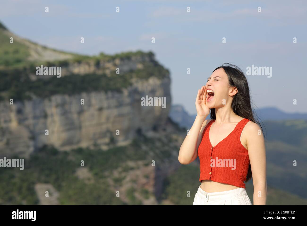 Donna asiatica urlando forte in montagna durante le vacanze estive Foto Stock