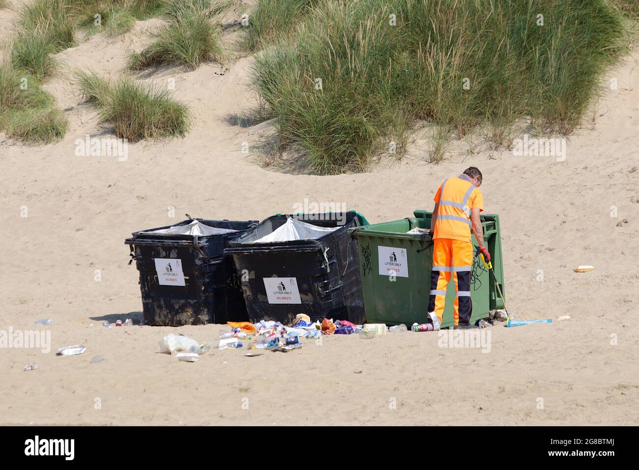 Campanatura, Sussex orientale, Regno Unito. 19 Jul 2021. Tempo in Gran Bretagna: Caldo e soleggiato sulle lunghe miglia spiagge sabbiose di Camber Sands nel Sussex orientale. Lavoratore del consiglio che raccoglie la lettiera dalla spiaggia accanto ai contenitori commerciali dei rifiuti. Photo Credit: Paul /Alamy Live News Foto Stock