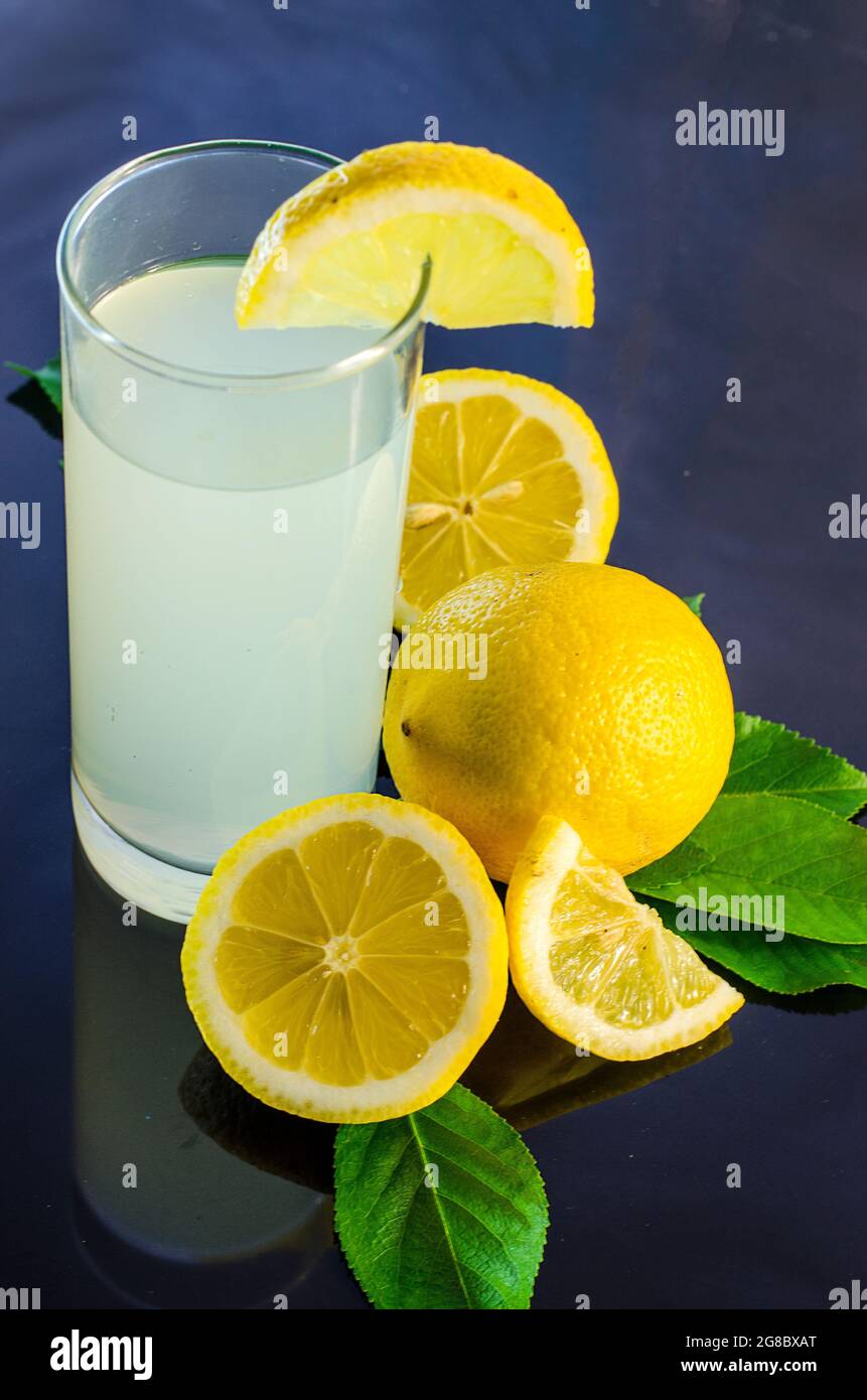 succo di limone fresco e limone su sfondo scuro Foto Stock