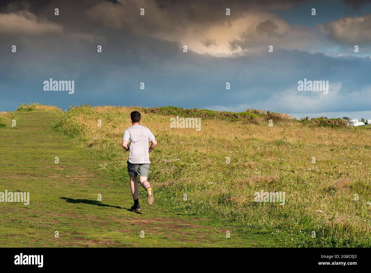 Un uomo che corre lungo la Warren su Pentire Point East a Newquay in Cornovaglia. Foto Stock
