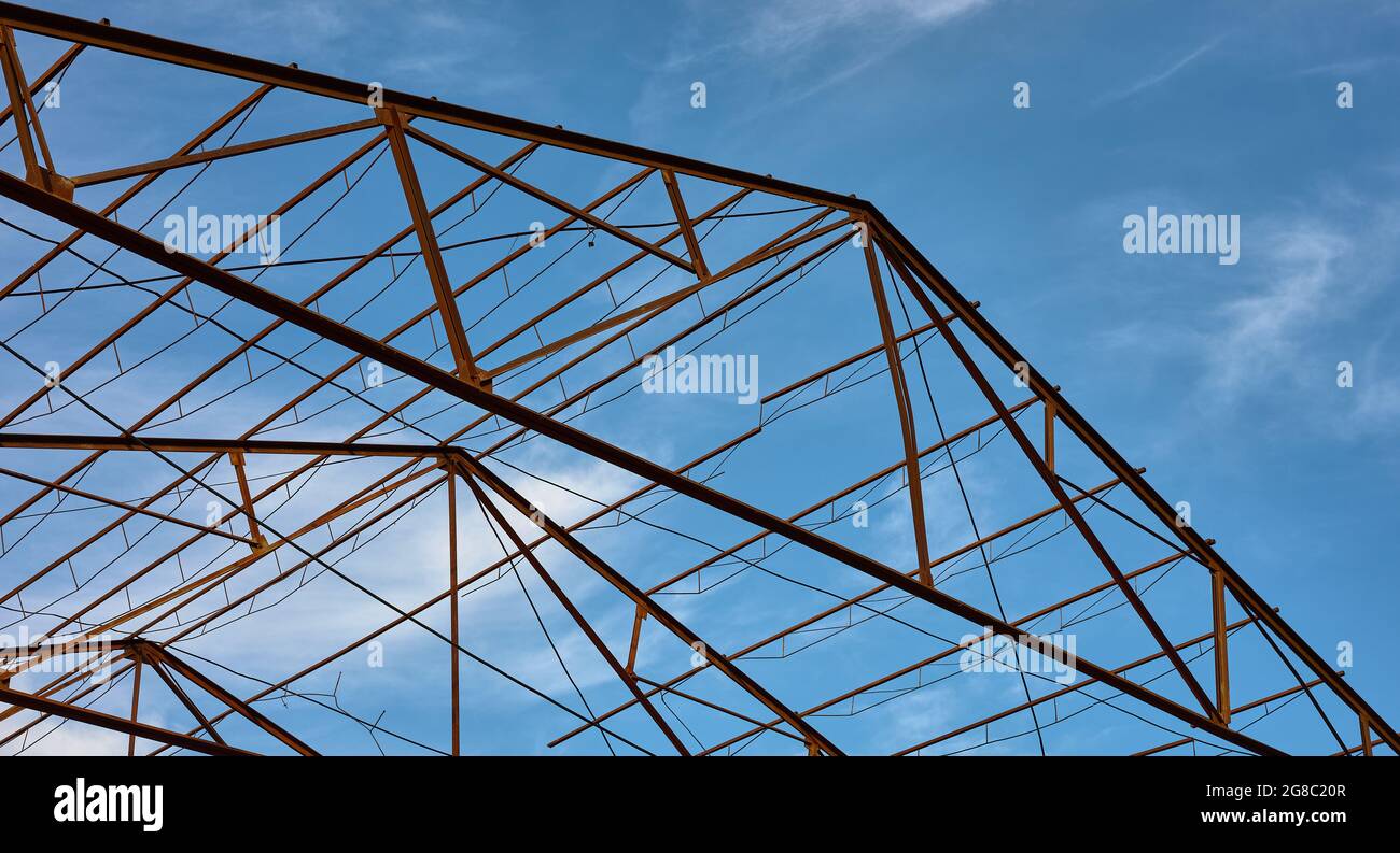particolare di una struttura metallica di un tetto abbandonato contro un cielo blu Foto Stock