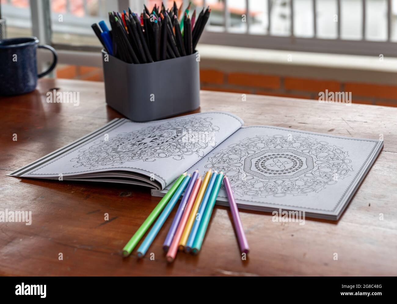 libro mandala per colorare con i pastelli in una scrivania in ufficio domestico Foto Stock