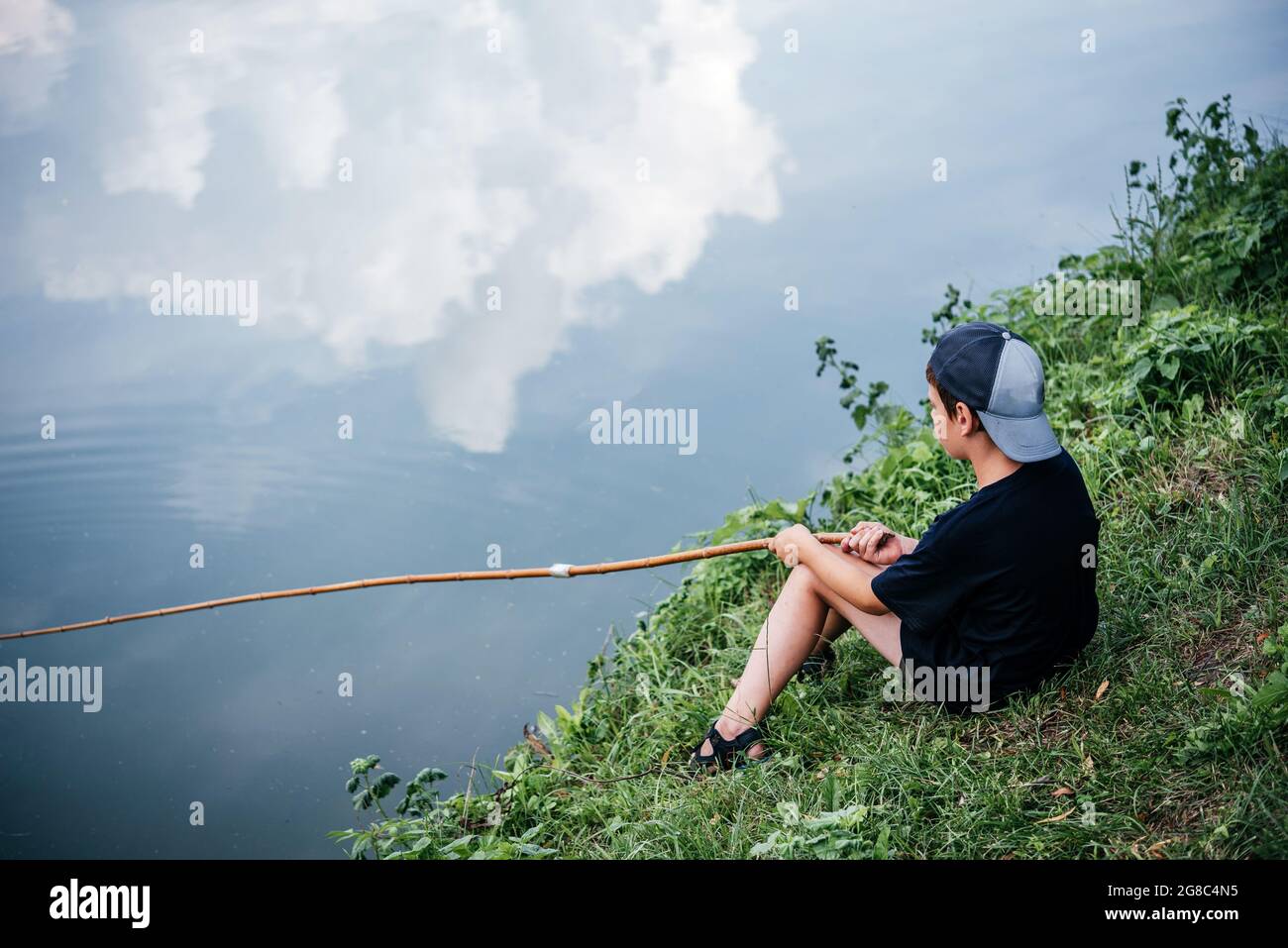 Un ragazzo che tiene una canna da pesca e la pesca nel lago, attività  estive e hobby per i bambini Foto stock - Alamy