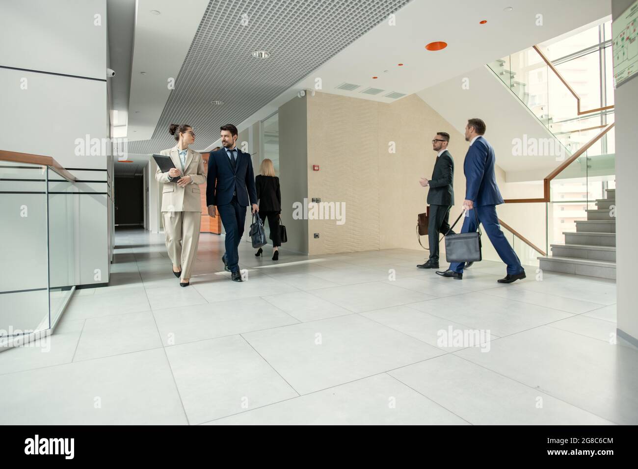 Gruppo di uomini d'affari che camminano attraverso il corridoio dell'ufficio durante la giornata lavorativa Foto Stock