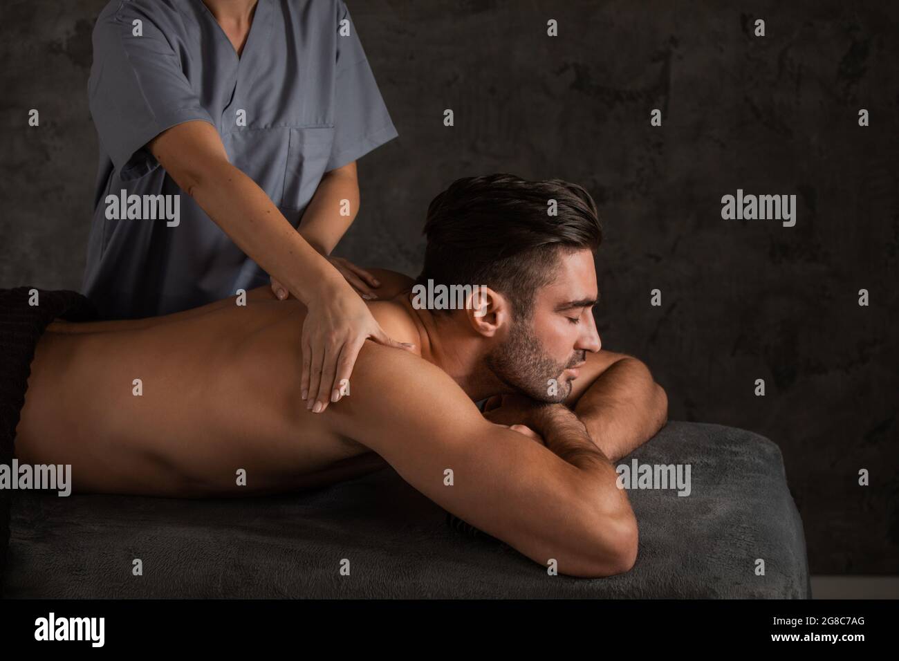 Un uomo che guarda bene che ottiene un massaggio della schiena disteso giù Foto Stock