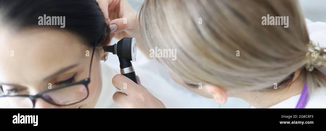 Otorhinolaringologo medico che esamina pazienti orecchio con otoscopio in clinica Foto Stock
