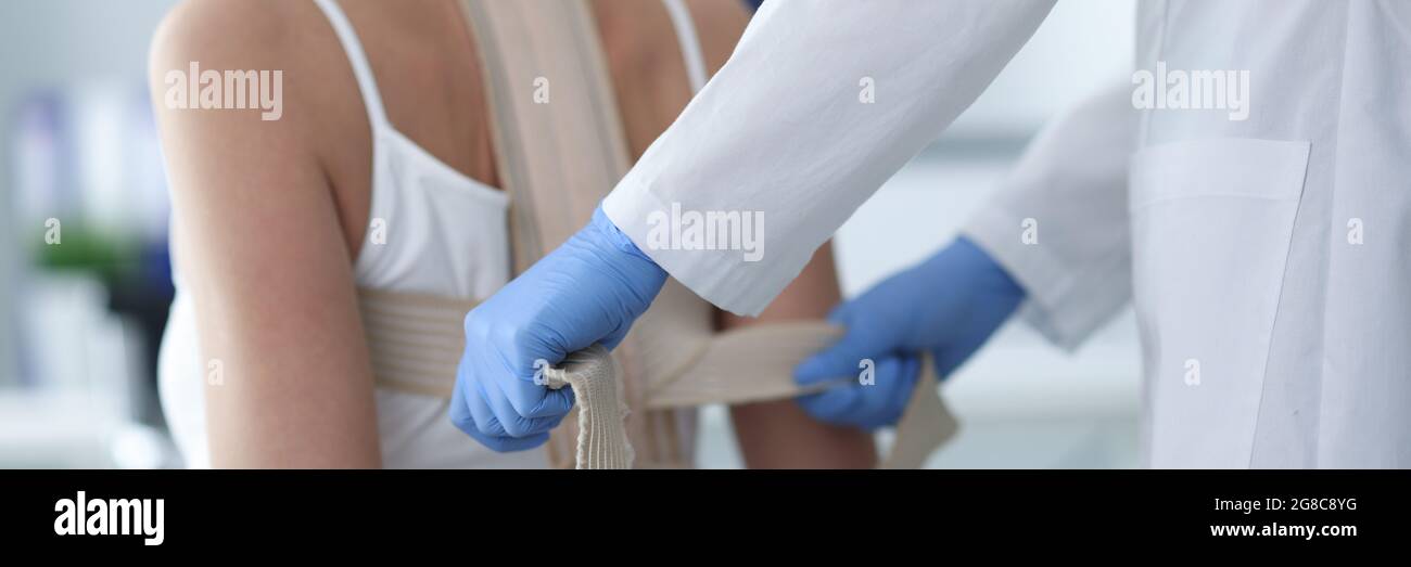 Medico che mette il corset sulla parte posteriore del closeup del paziente femminile Foto Stock