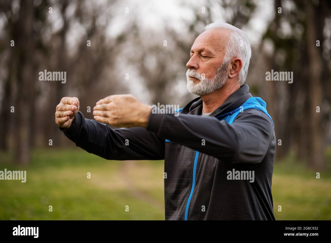 L'uomo anziano sta praticando l'esercitazione del chi del Tai nel parco. Foto Stock