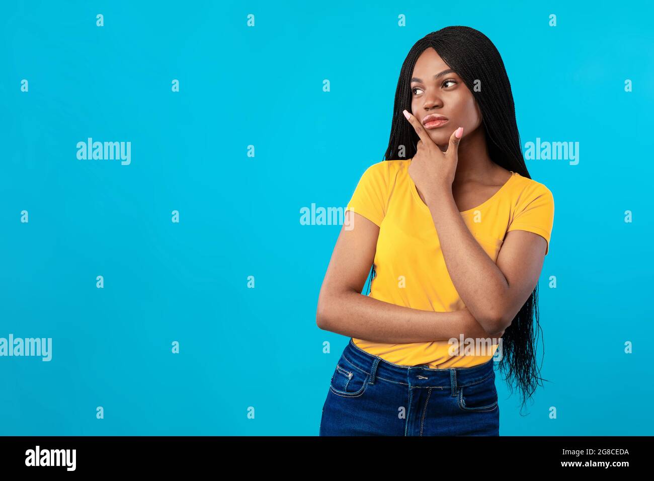 African American Lady Thinking in piedi vicino spazio vuoto, sfondo blu Foto Stock