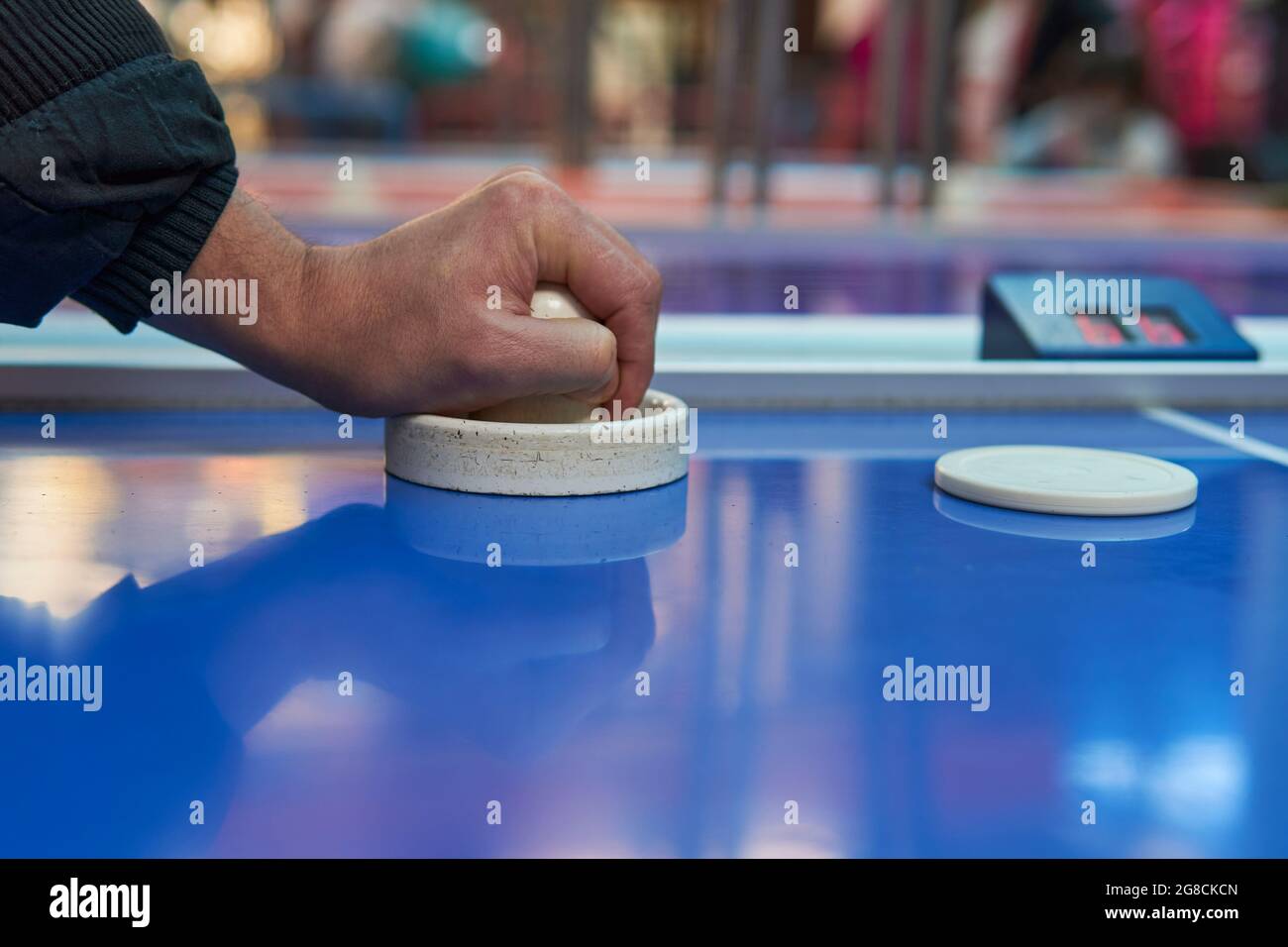 Mano di bruna uomo che tiene attaccante su tavolo da hockey in sala giochi. Orizzontale Foto Stock