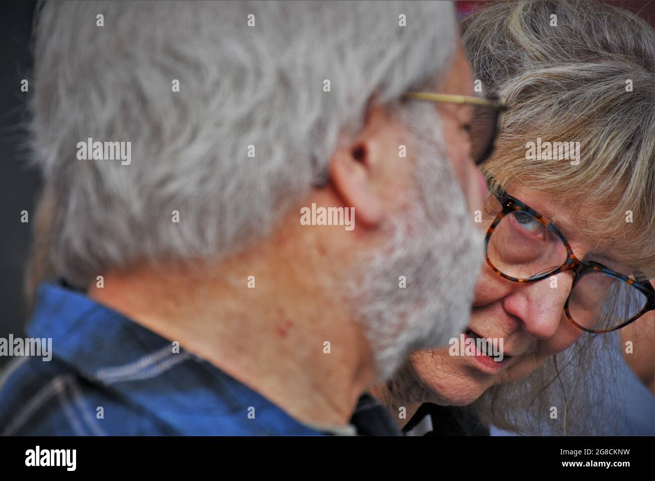 Sguardo scettico ad un uomo da una donna con gli occhiali durante una riunione, entrambi gli anziani Foto Stock