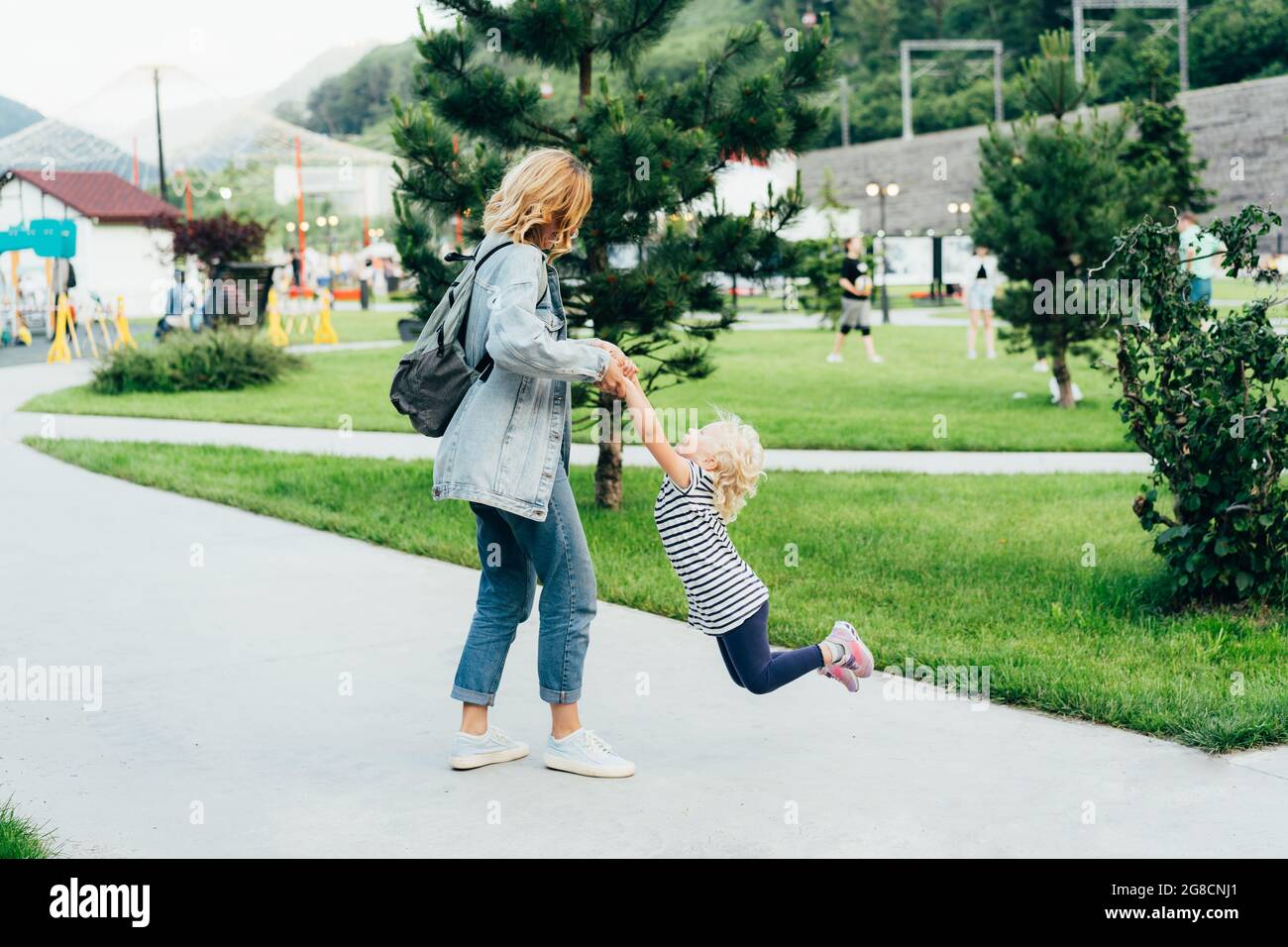Giovane mamma carina tormenterà la sua piccola adorabile figlia nel parco della città. Foto Stock