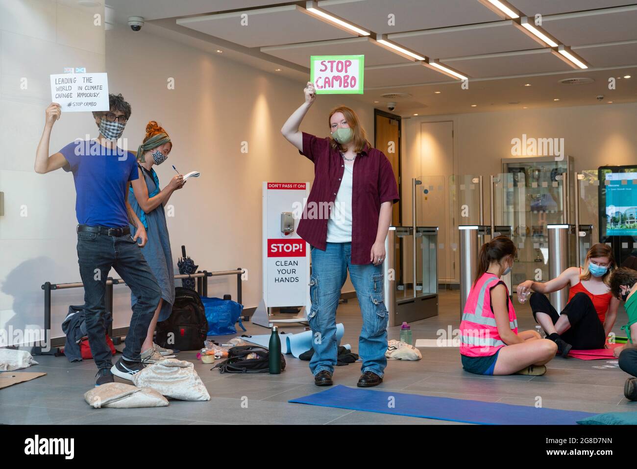 Edimburgo, Scozia, Regno Unito. 19 luglio 2021. I manifestanti si sono opposti all'approvazione del nuovo giacimento di petrolio e gas del Mare del Nord di Cambo occupano oggi la casa della Regina Elisabetta del Governo HM nel centro di Edimburgo. I manifestanti sono ancora all'interno e all'esterno dell'edificio nel pomeriggio sotto la sorveglianza della polizia. I manifestanti citano il riscaldamento globale e il cambiamento climatico come una ragione per lasciare tutti i nuovi depositi di petrolio e gas nel terreno non sviluppati. PIC; manifestanti seduti all'interno del foyer della casa della regina Elisabetta . Iain Masterton/Alamy Notizie dal vivo. Foto Stock