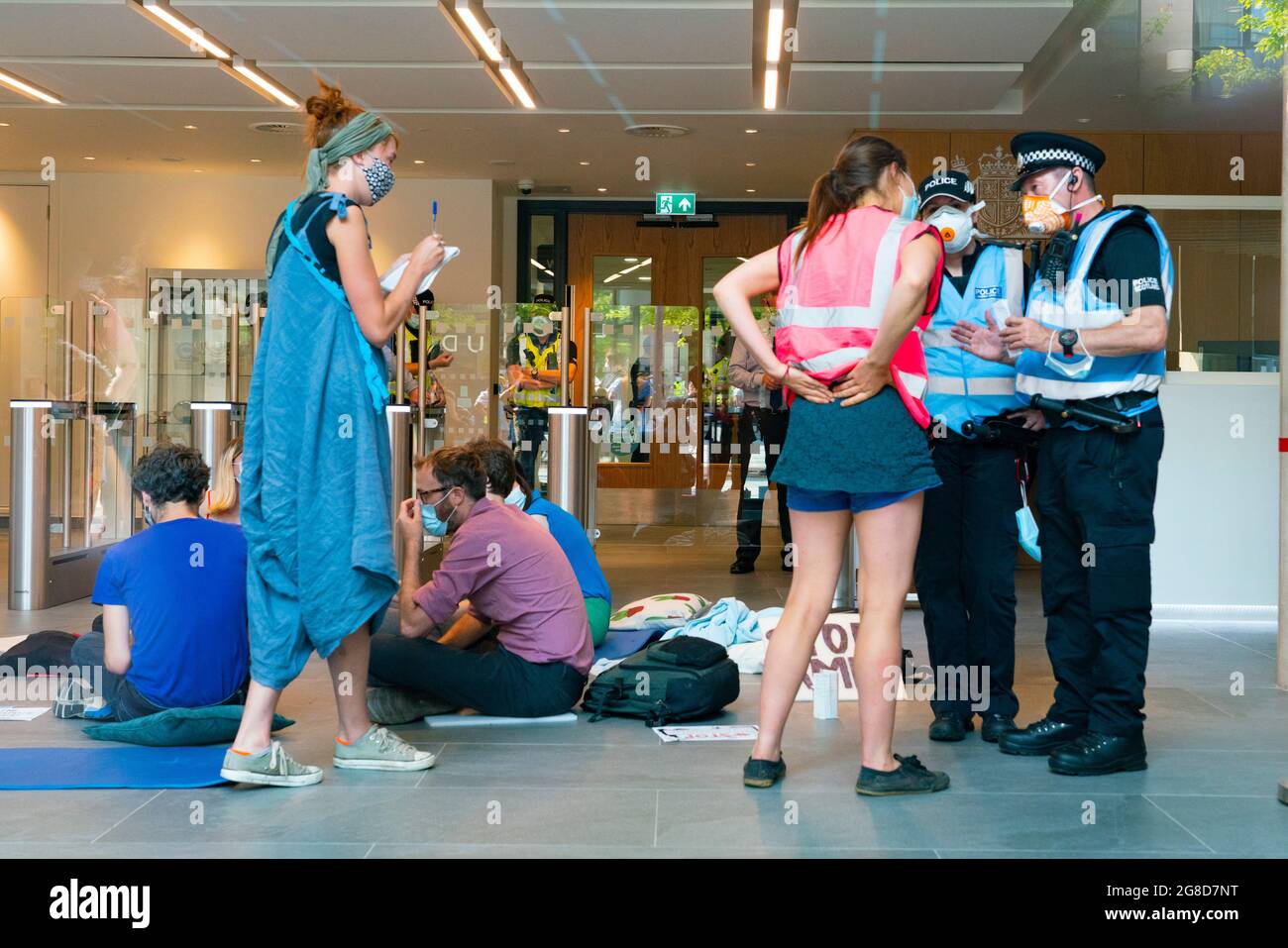 Edimburgo, Scozia, Regno Unito. 19 luglio 2021. I manifestanti si sono opposti all'approvazione del nuovo giacimento di petrolio e gas del Mare del Nord di Cambo occupano oggi la casa della Regina Elisabetta del Governo HM nel centro di Edimburgo. I manifestanti sono ancora all'interno e all'esterno dell'edificio nel pomeriggio sotto la sorveglianza della polizia. I manifestanti citano il riscaldamento globale e il cambiamento climatico come una ragione per lasciare tutti i nuovi depositi di petrolio e gas nel terreno non sviluppati. PIC; manifestanti seduti all'interno del foyer della casa della regina Elisabetta . Iain Masterton/Alamy Notizie dal vivo. Foto Stock