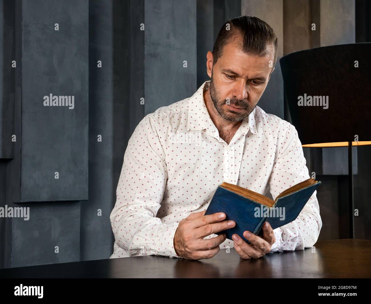 L'uomo legge il libro vintage nella stanza buia. Foto Stock
