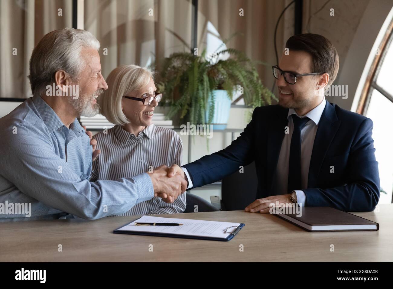 Felice anziano sposato coppia scuotendo le mani con il realtor Foto Stock