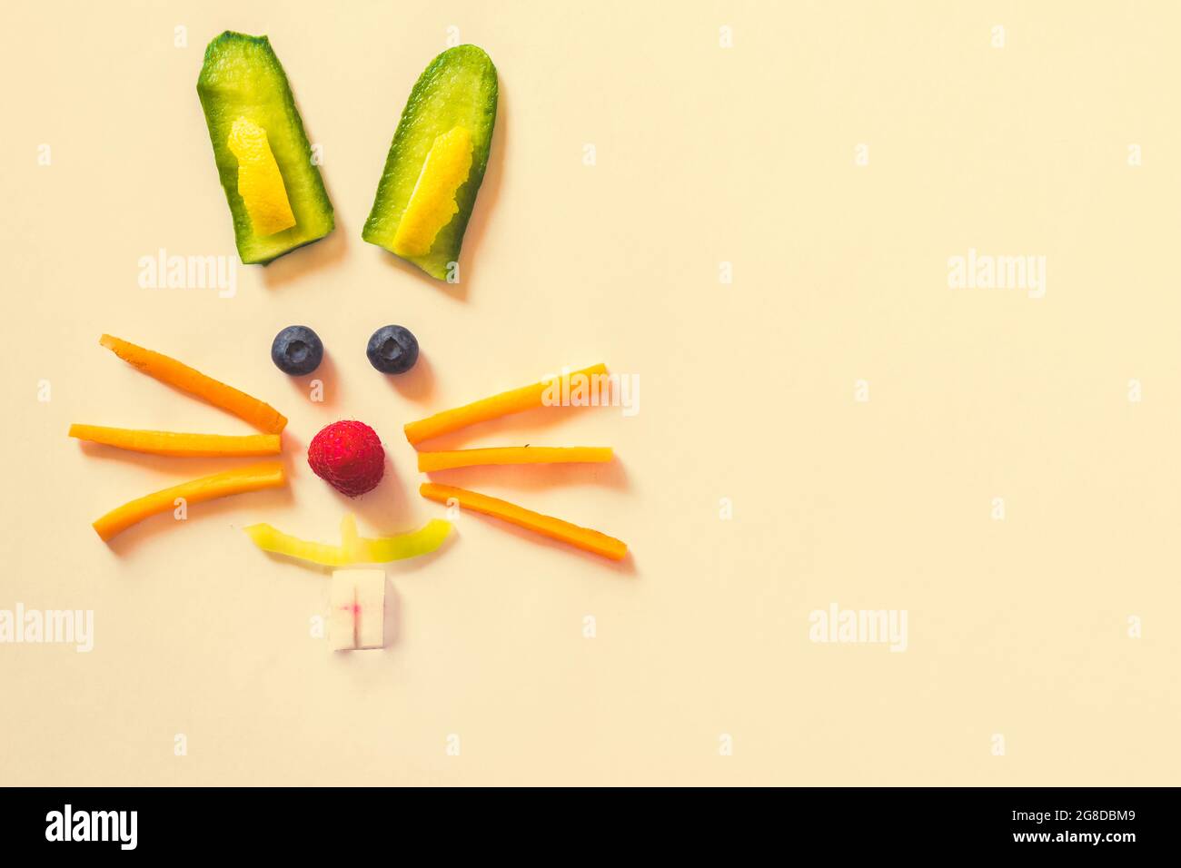 Faccia di coniglio fatta da pezzi di frutta e verdura, isolata su sfondi gialli, concetto di Pasqua felice Foto Stock