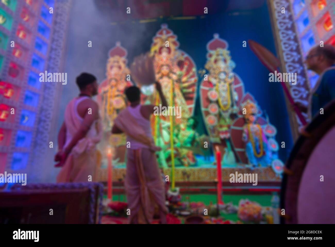 Immagine offuscata di Dhaakis, giocando dhaaks mentre il prete indù bengalese adora la dea Durga con il camor, Durga aarti sotto il fumo santo durante Durga Puja Foto Stock