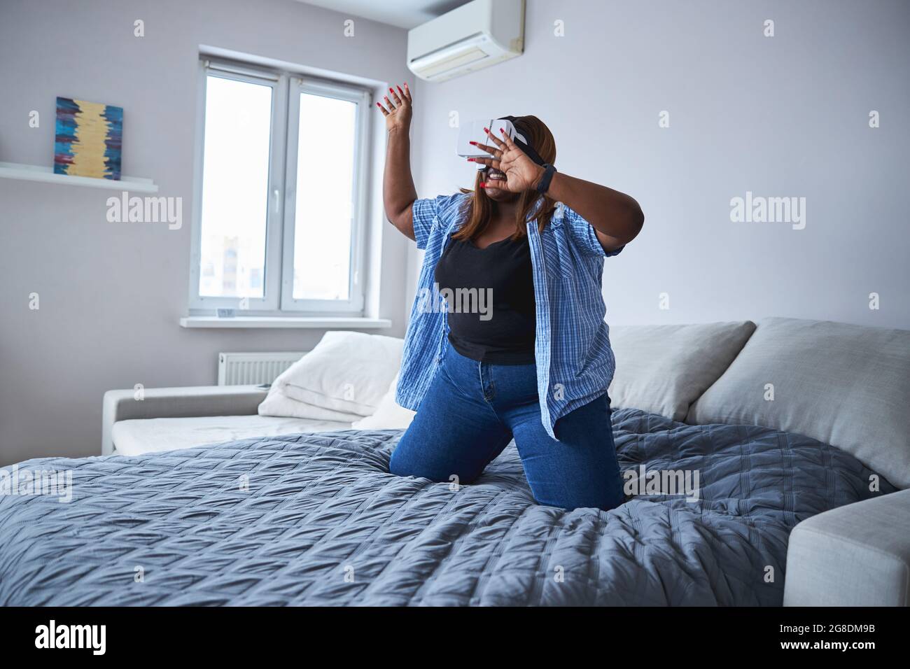 Donna espressiva che prova il gadget di realtà virtuale a casa Foto Stock