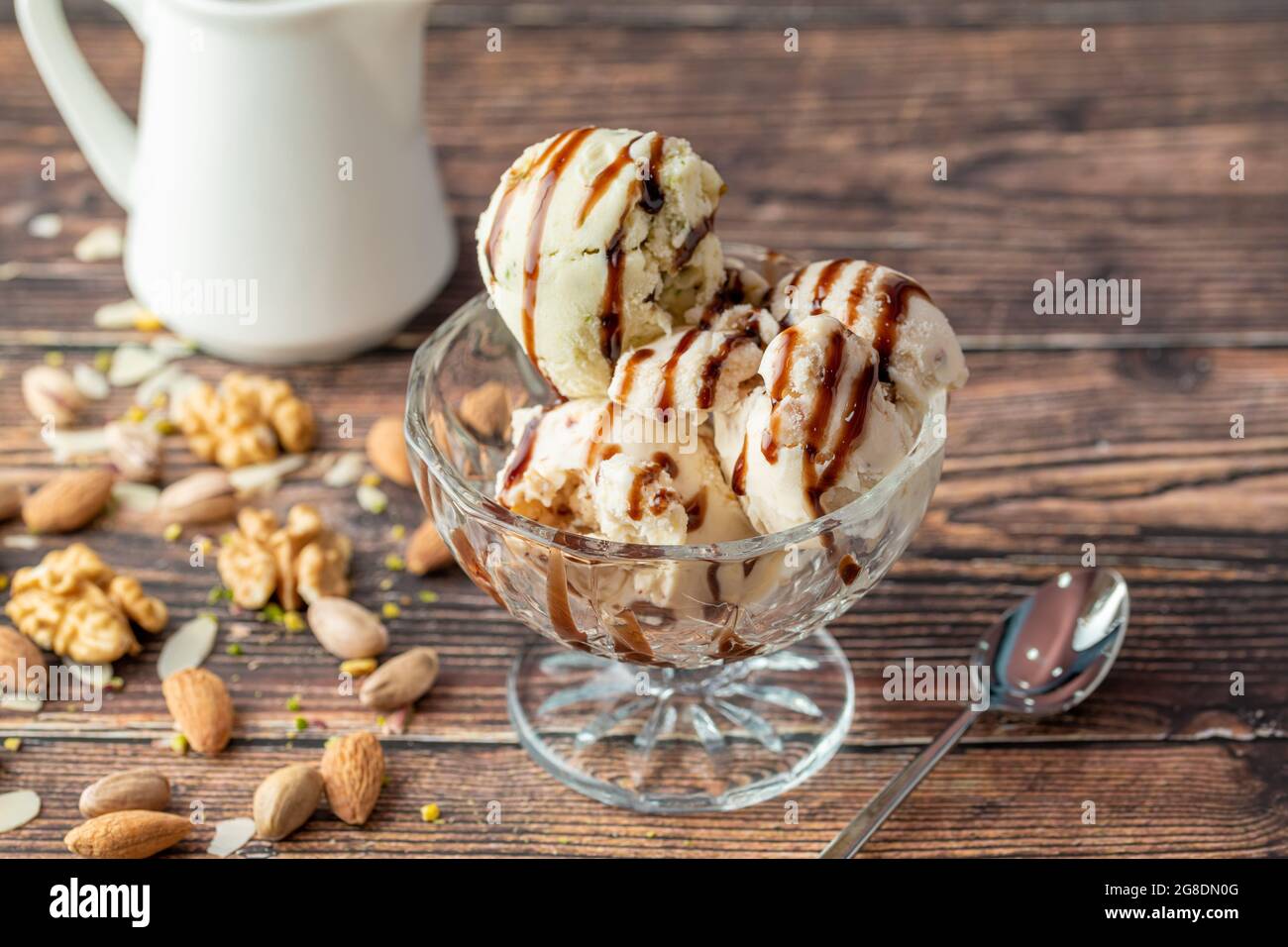Gelato di mandorle, pistacchio e noce Roma in una ciotola di vetro con salsa al caramello. Foto Stock