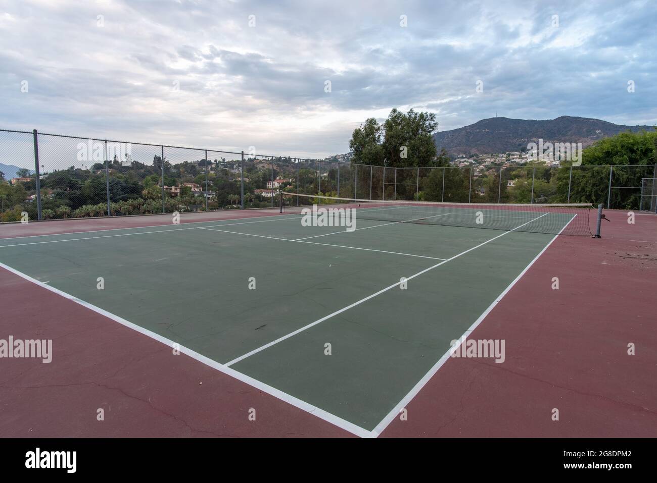 Le nuvole tropicali all'alba diffondono la luce del mattino sulle doppie linee del campo da tennis duro. Foto Stock