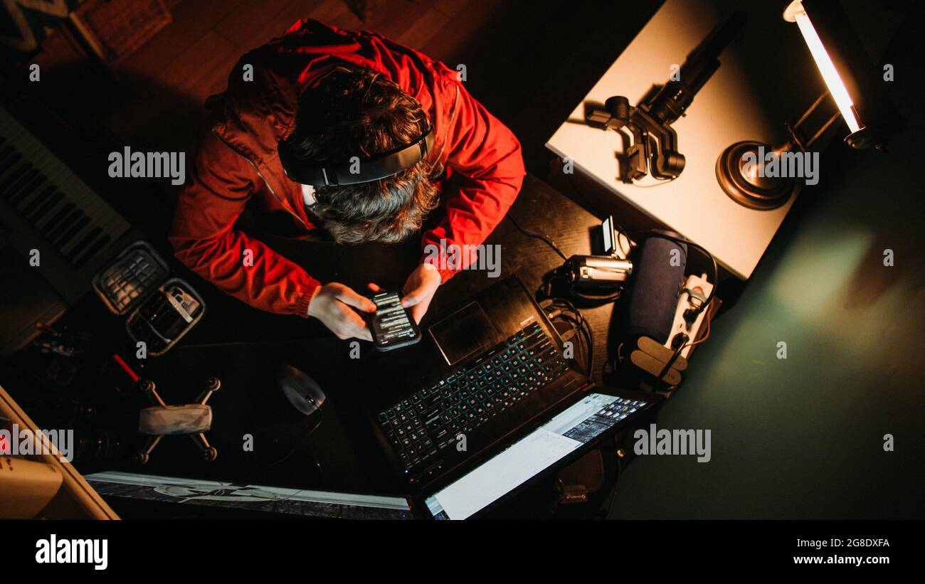 Uomo Content Creator duro al lavoro alla sua scrivania a tarda notte, stressato, stanco Foto Stock