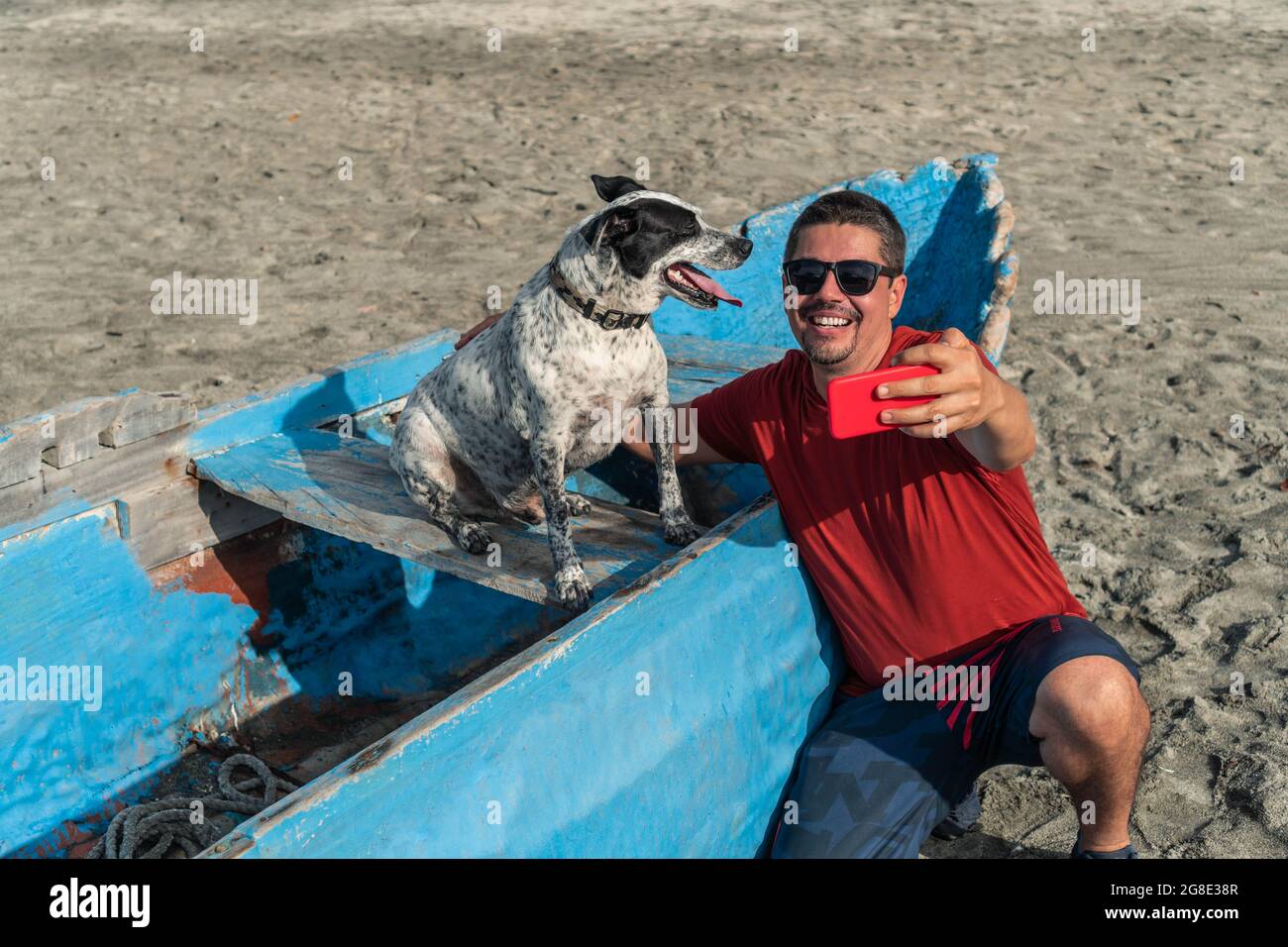 Uomo che prende un selfie con il suo cane sulla spiaggia in estate Foto Stock
