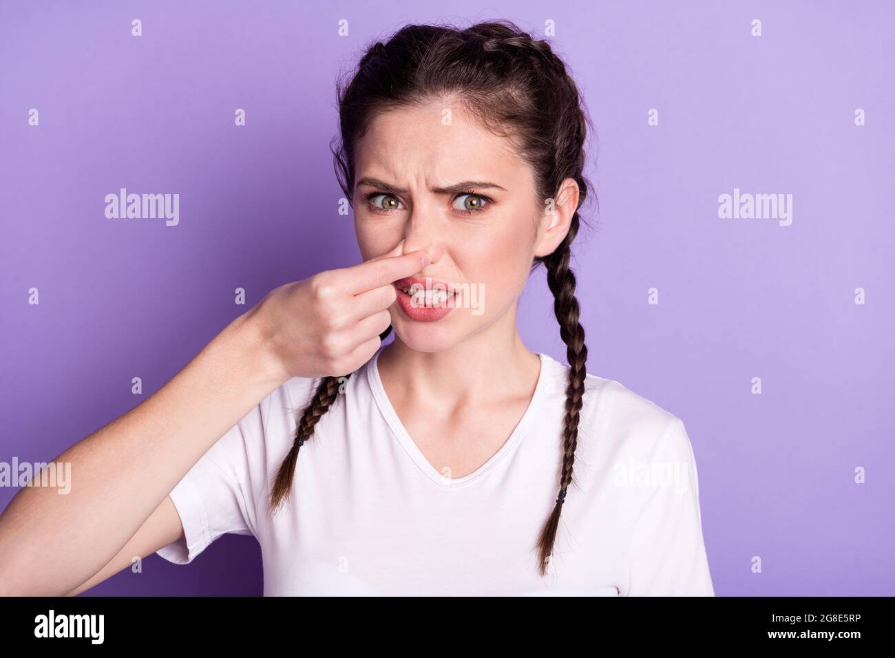 Ritratto di insoddisfatto giovane ragazza braccio tenere vicino naso Guarda fotocamera cattivo aromatat isolato su sfondo colore viola Foto Stock