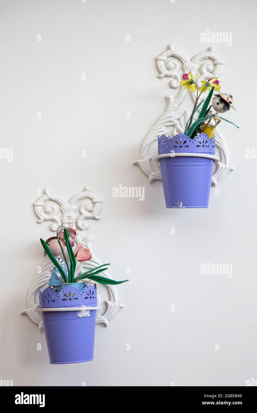 particolare di vasi di fiori di metallo appesi su una parete bianca, piante decorative colorate che crescono, oggetti Foto Stock