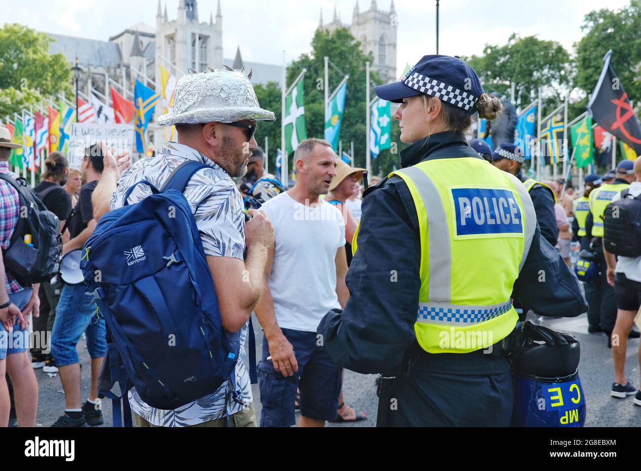 Un ufficiale di polizia si impegna con un protettore che indossa un cappello di stagno-foglio il giorno di Freedon in Piazza del Parlamento. Foto Stock