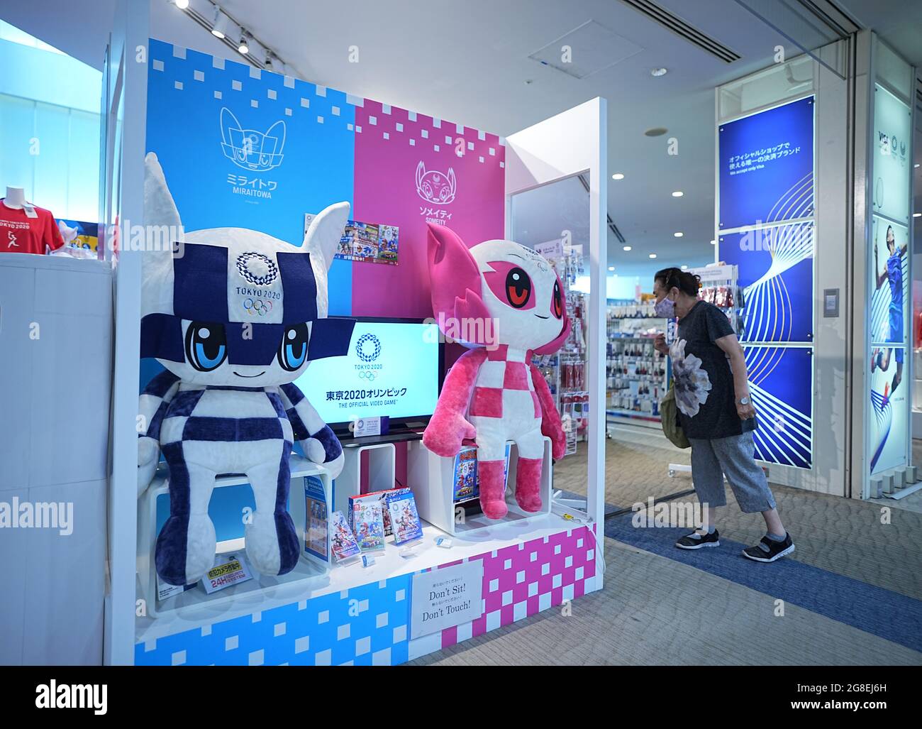 Tokio, Giappone. 20 luglio 2021. Una donna entra in un negozio di fan dei Giochi Olimpici. Le Olimpiadi di Tokyo 2020 si terranno dal 23.07.2021 al 08.08.2021. Credit: Michael Kappeler/dpa/Alamy Live News Foto Stock