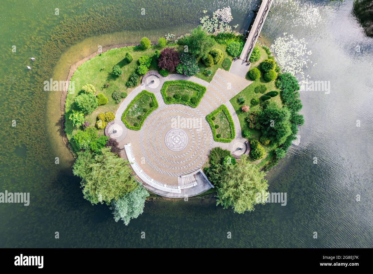 piccola isola sul laghetto con passerella in legno nel giardino botanico durante il giorno d'estate. vista aerea dall'alto Foto Stock