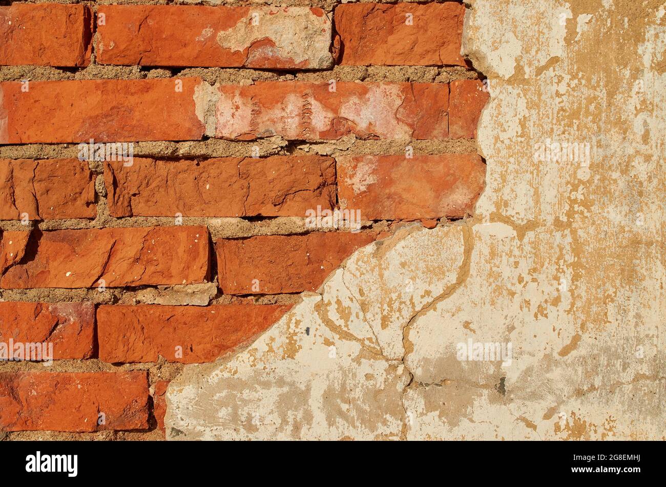 Il muro è fatto di mattoni rossi con intonaco caduto. Sfondo. Foto Stock