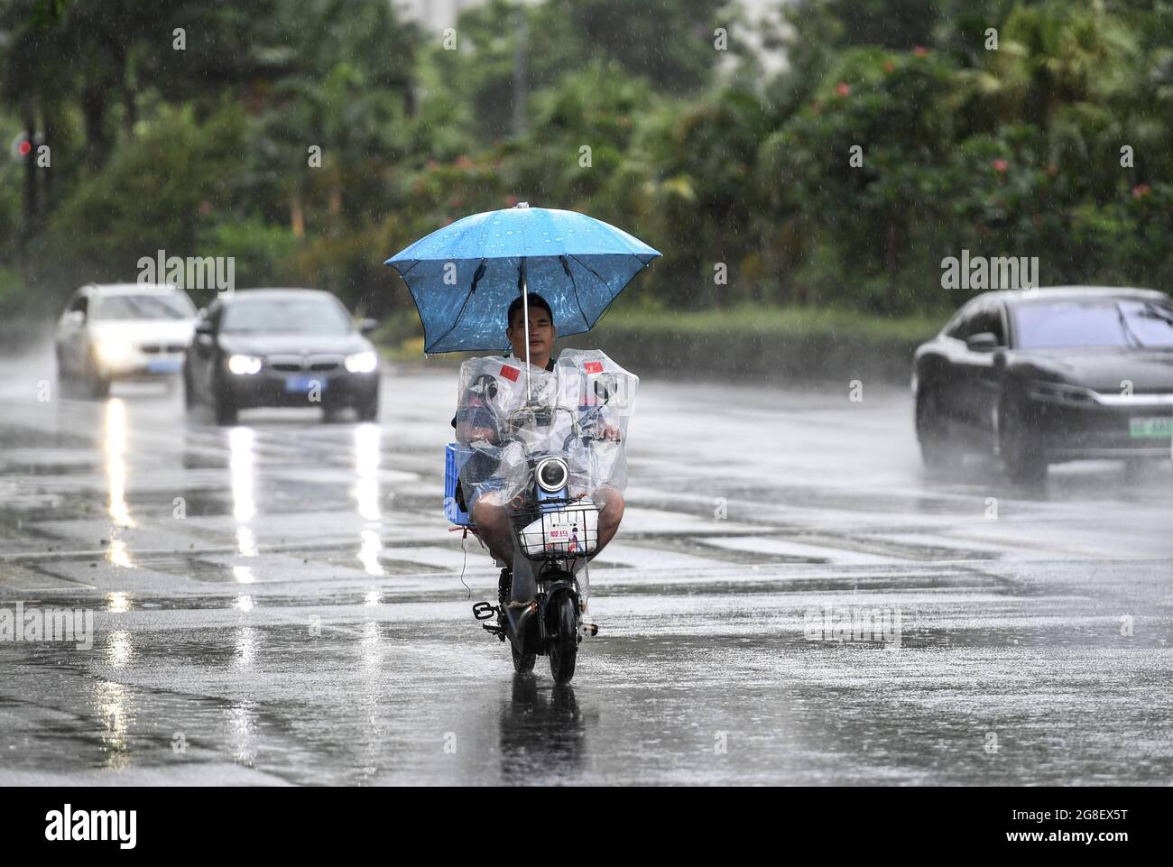 (210720) -- SHENZHEN, 20 luglio 2021 (Xinhua) -- UN residente guida una bicicletta elettrica sotto la pioggia a Shenzhen, provincia di Guangdong della Cina meridionale, 19 luglio 2021. Secondo le autorità meteorologiche provinciali, Typhoon Cempaka, il settimo di quest'anno, dovrebbe fare la caduta sulla costa della provincia di Guangdong, nella Cina meridionale, martedì. Cempaka, che si rafforzerà in un tifone il lunedì mattina, si avvicinerà lentamente alla regione costiera tra l'estuario del fiume Pearl e il Guangdong occidentale, con la sua intensità crescente gradualmente, e farà la caduta tra le città di Zhuhai e Maoming tra Mar Foto Stock