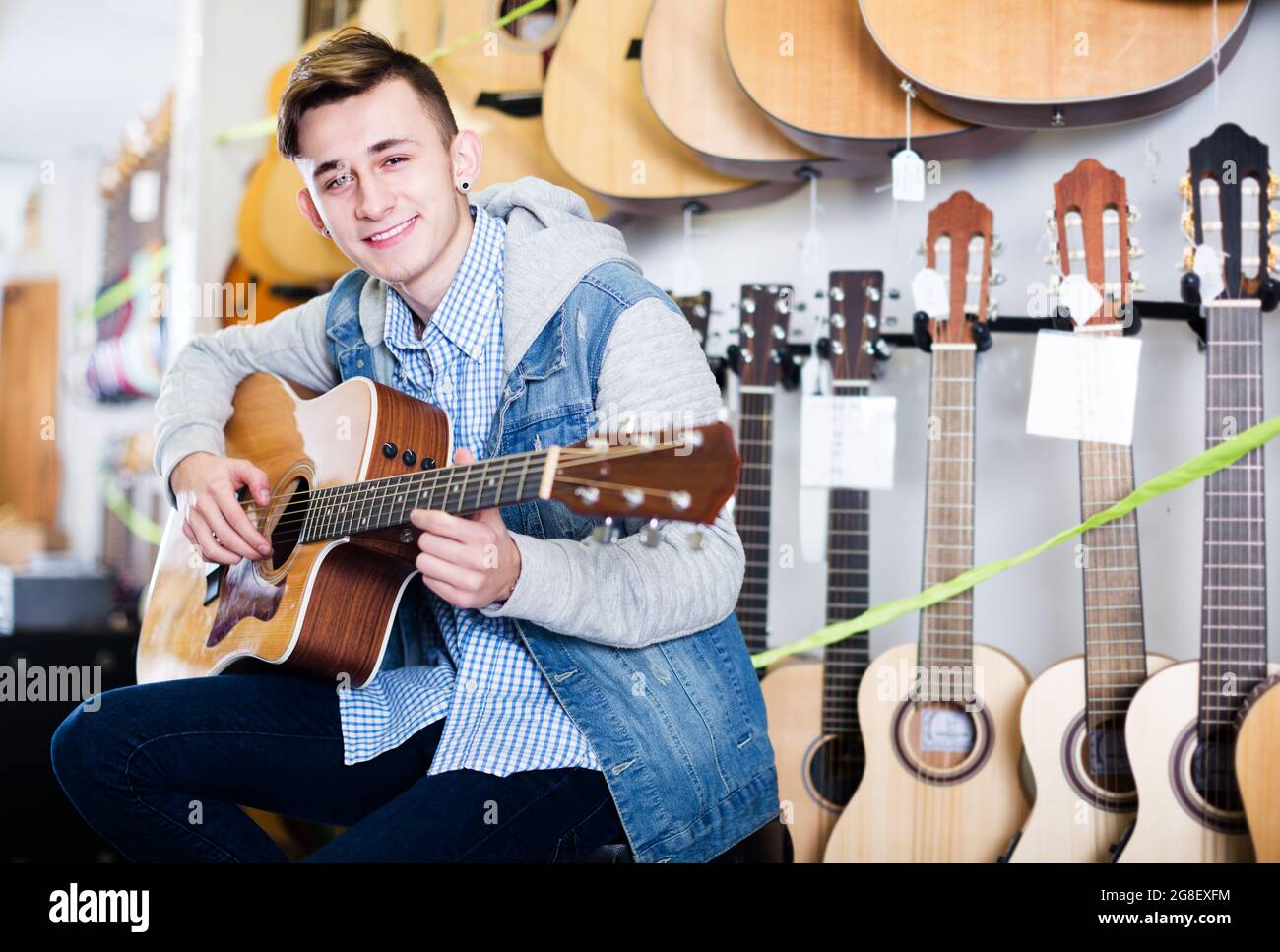 Teenager che sceglie chitarre acustiche Foto Stock