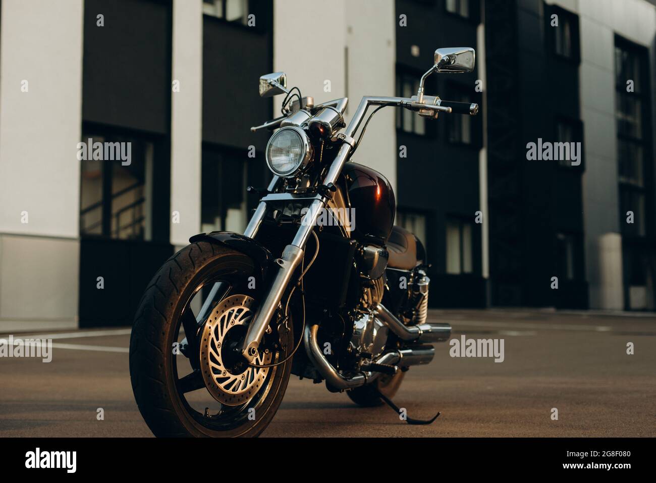 Una motocicletta in un parcheggio nella calda luce di un tramonto. Elegante motobike chopper personalizzato con dettagli cromati. Libertà di movimento in moto. SEL. Morbida Foto Stock