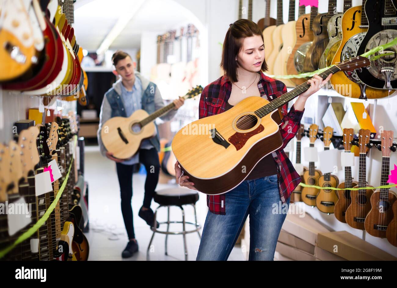 i clienti adolescenti decidono di utilizzare una chitarra acustica adatta nel negozio di chitarra Foto Stock