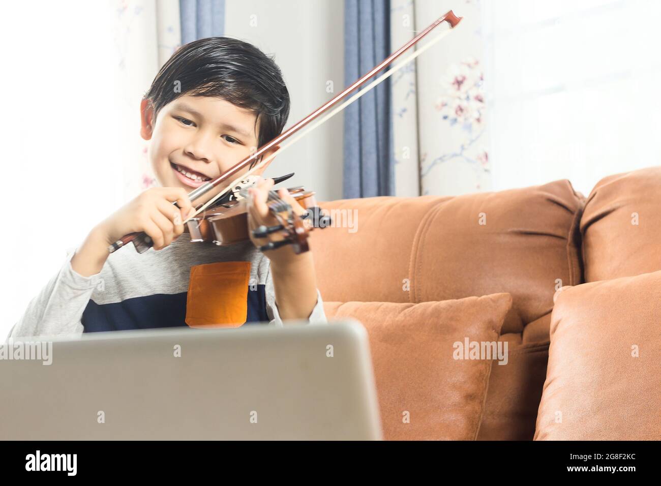 Un ragazzo sorridente impara a suonare il violino con lezioni online.  Guarda la fotocamera Foto stock - Alamy