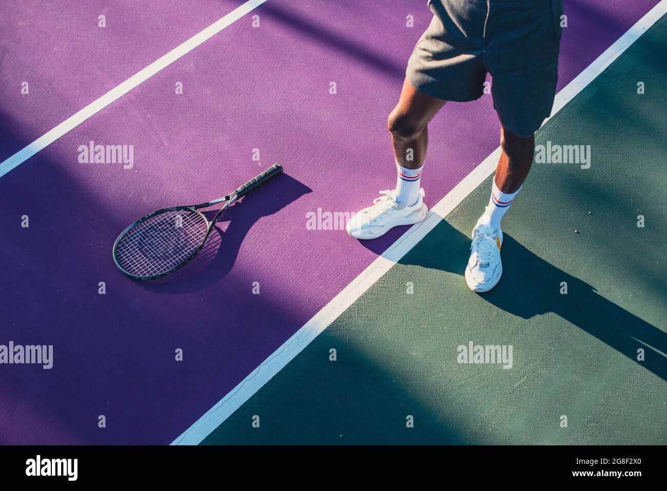 Uomo in piedi sul campo da tennis con racchetta accanto a lui Foto Stock