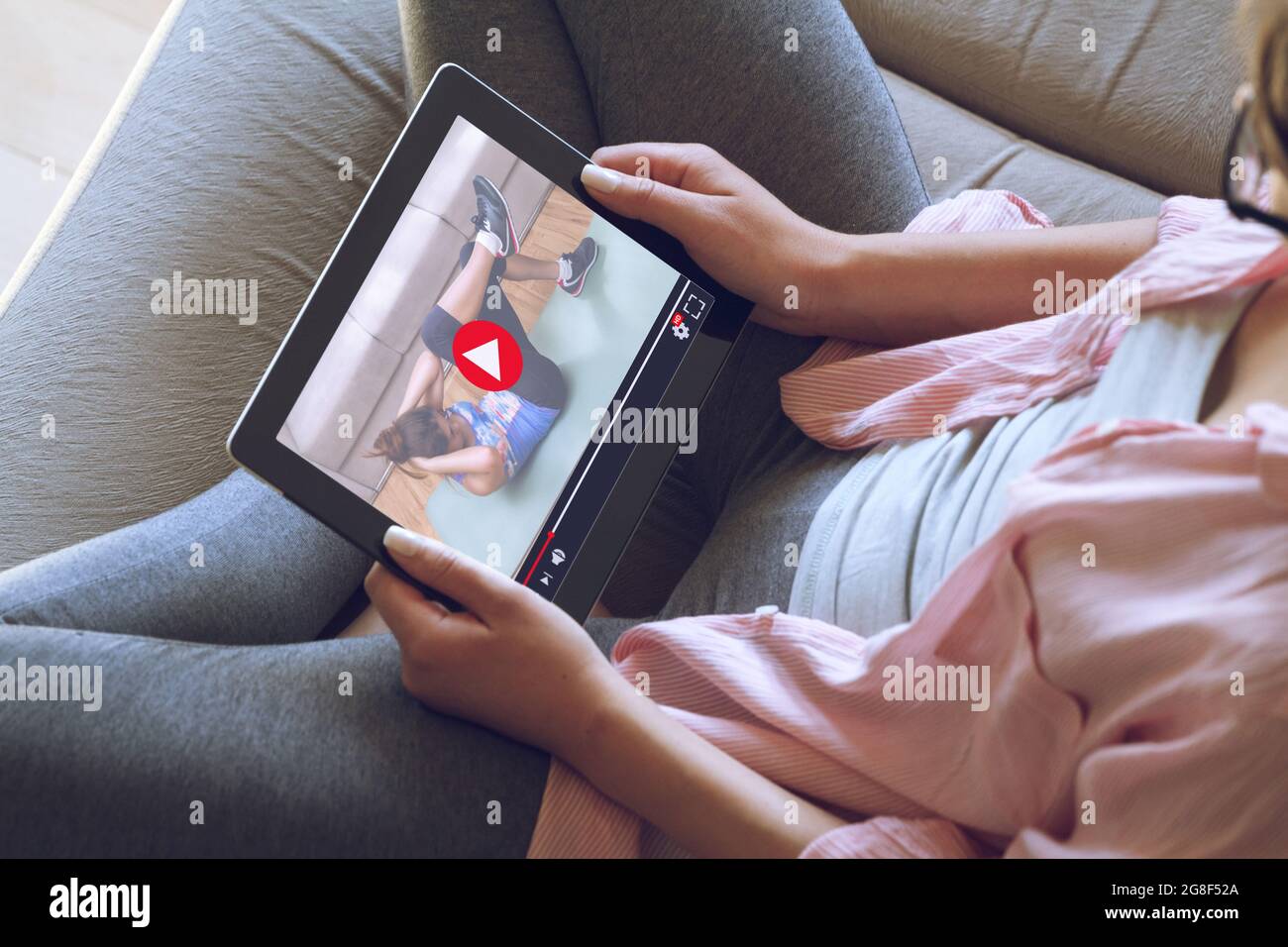 Donna che tiene un tablet digitale e guarda tutorial video online sul fitness. Foto Stock