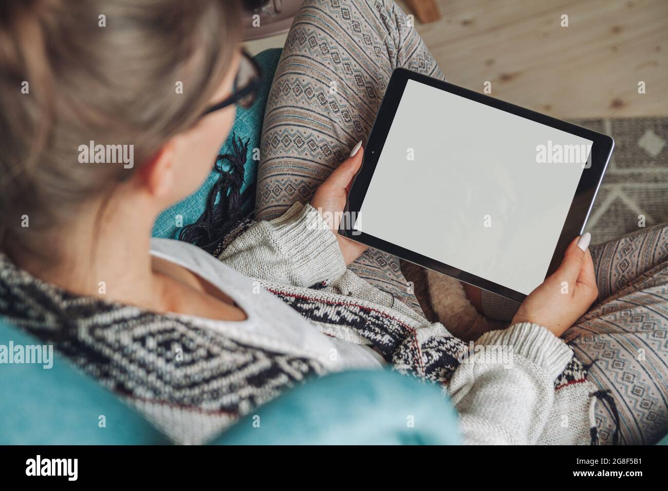 donna seduta in comoda poltrona, con coperta calda, con tablet Foto Stock