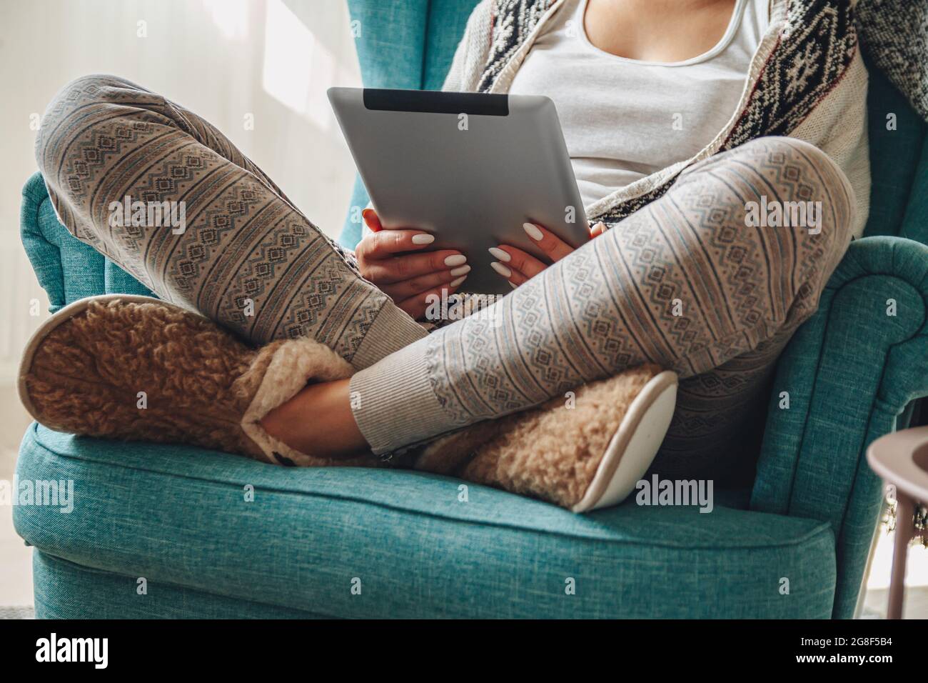 donna seduta in comoda poltrona, con coperta calda, con tablet Foto Stock