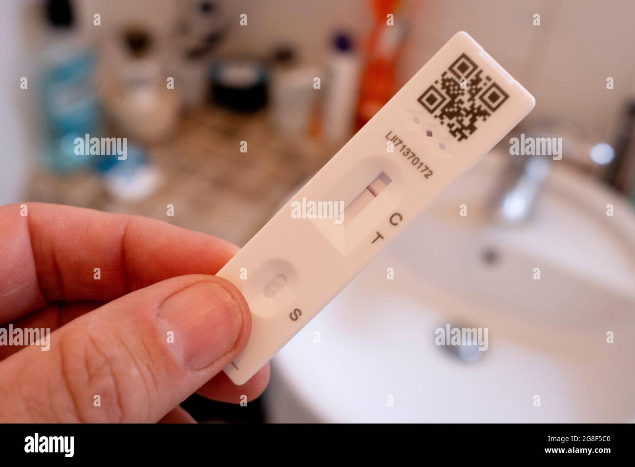 Un dettaglio di una mano che tiene un test di flusso laterale che mostra un risultato negativo in un bagno domestico il 'Freedom Day', 19 luglio 2021, a Londra, Inghilterra. La "Giornata della libertà" è la data in cui il governo britannico del primo ministro Boris Johnson ha fissato la fine delle pandemie di condizioni di allontanamento sociale di Covid con la fine delle coperture obbligatorie dei volti nei negozi e nei trasporti pubblici. Foto Stock