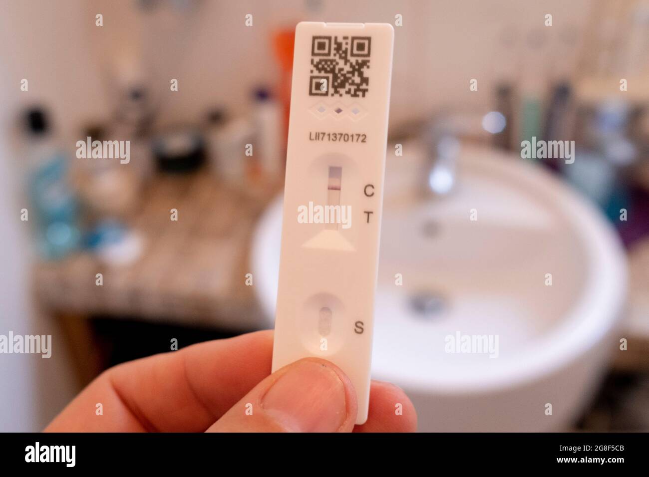 Un dettaglio di una mano che tiene un test di flusso laterale che mostra un risultato negativo in un bagno domestico il 'Freedom Day', 19 luglio 2021, a Londra, Inghilterra. La "Giornata della libertà" è la data in cui il governo britannico del primo ministro Boris Johnson ha fissato la fine delle pandemie di condizioni di allontanamento sociale di Covid con la fine delle coperture obbligatorie dei volti nei negozi e nei trasporti pubblici. Foto Stock