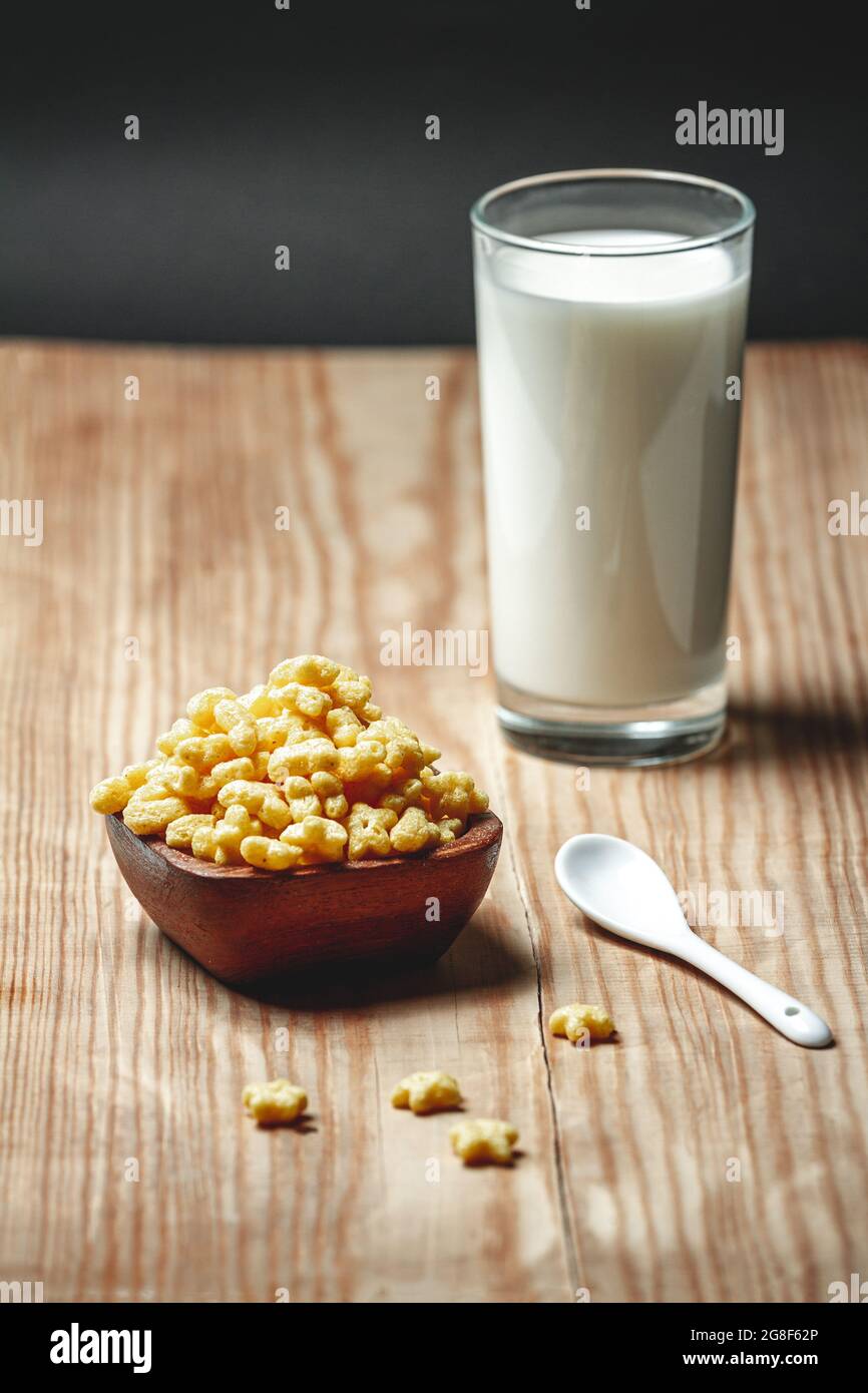 Ciotola in legno con cereali per la colazione rapida e un bicchiere di latte Foto Stock