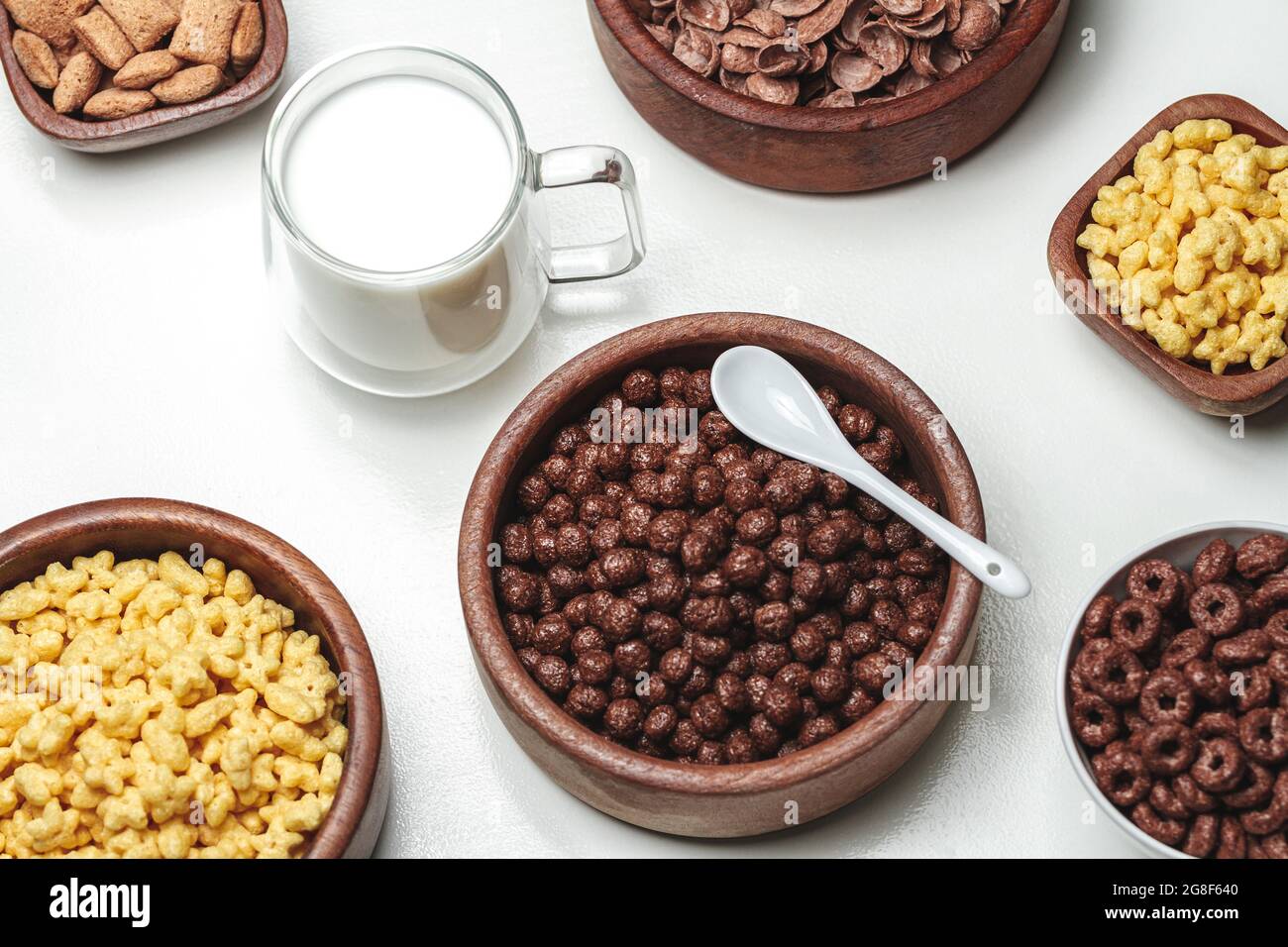 Ciotole con diversi tipi di prodotti a base di cereali per la colazione e vetro Foto Stock