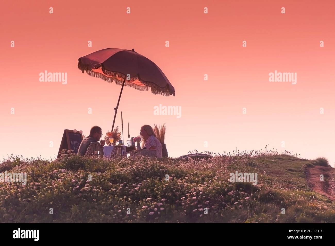Una coppia festeggia un'occasione speciale con un romantico picnic serale a Towan Head a Newquay in Cornovaglia. Foto Stock