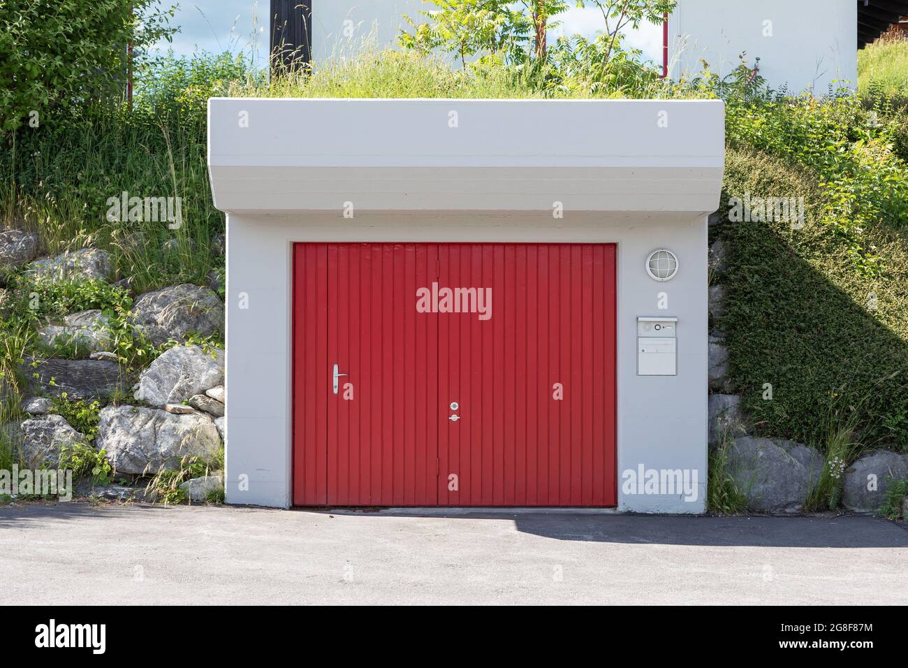 garage in cemento nel giardino con cancello rosso Foto Stock