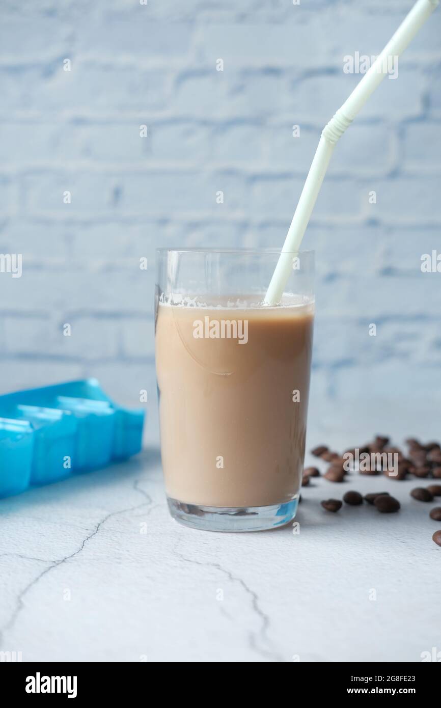 ghiaccio il caffè in un bicchiere alto con i chicchi di caffè sul tavolo Foto Stock