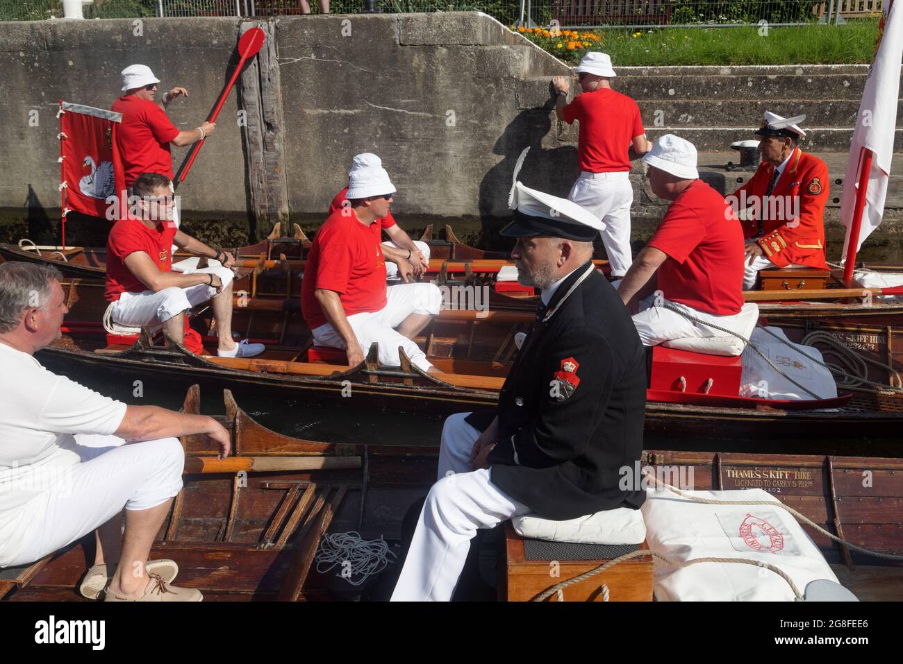 Boveney Lock, vicino Eton, Regno Unito: 20 luglio 2021. Annuale Swan Upping censimento della popolazione cigno sul fiume Tamigi. I ruscelli della Worshipful Company of Vintners e della Worshipful Company of Dyers si sollevano lungo il fiume in tradizionali skiffs con il marcatrice della regina David Barber (blazer scarlatto). Si ritiene che l'evento annuale risalga al 1189, quando la Corona rivendicò la proprietà di tutti i cigni muti per il cibo per banchetti e feste. Oggi i cigneti sono pesati e misurati per ottenere stime dei tassi di crescita e sono esaminati per i segni di pregiudizio, di solito causato da ganci da pesca e lenza. Foto Stock